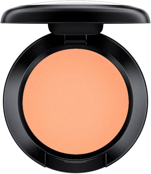 A round makeup blush in a black container, peach-colored and smooth.