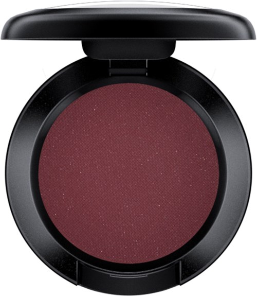 A round makeup compact with dark casing, open lid, and maroon-colored eyeshadow or blush inside.
