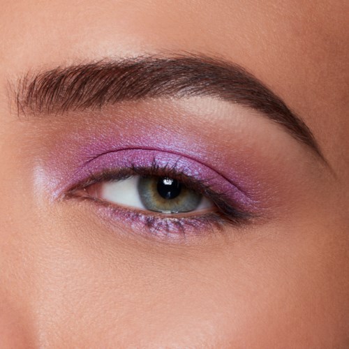 Close-up of an eye with purple eyeshadow and well-groomed eyebrow. Focus on makeup and eye details.