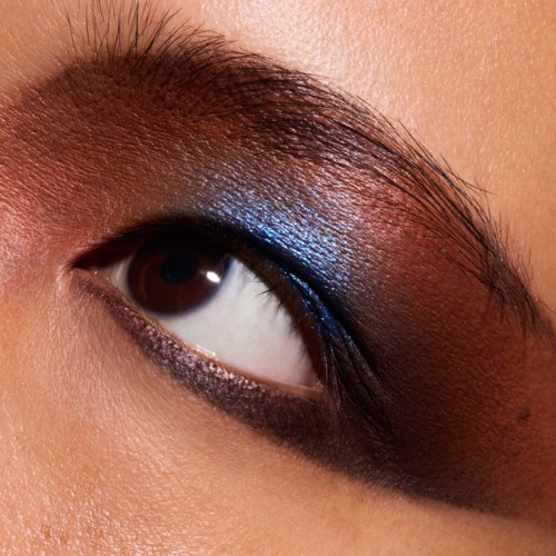 A person's eye with colorful eye makeup, including blue eyeshadow and dark eyeliner.