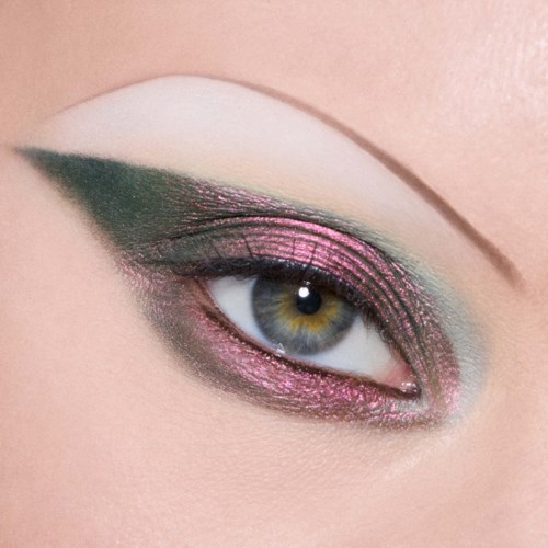 Close-up van oog met heldere roze en groene oogschaduw en dikke eyeliner. Oogkleur is hazel.