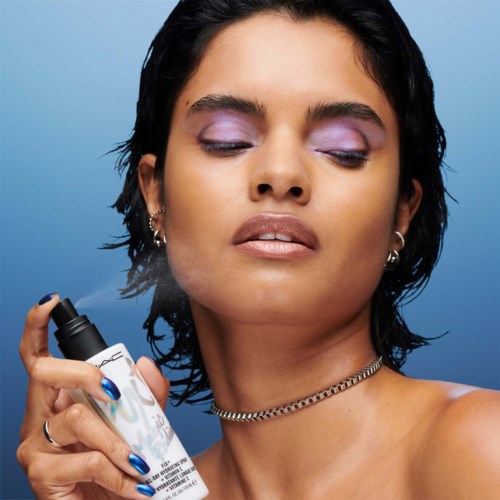 A woman sprays perfume on her neck with her eyes closed, looking confident and relaxed.