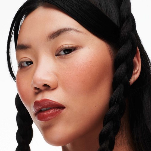 A woman with long black hair styled in two braids. She has light makeup and a confident look.