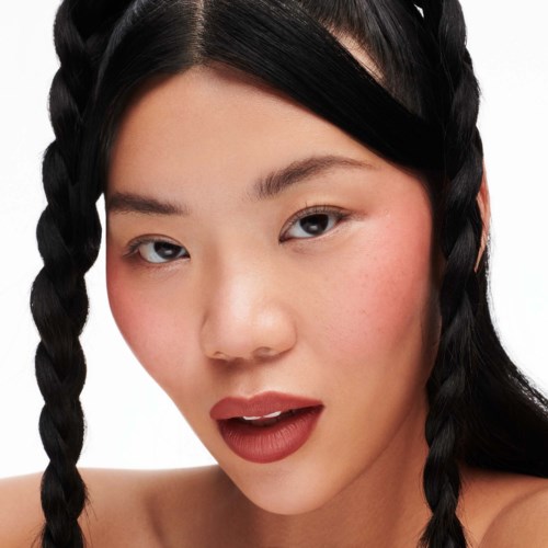 A young woman with black hair in two braids, slightly parted lips, and a confident expression.