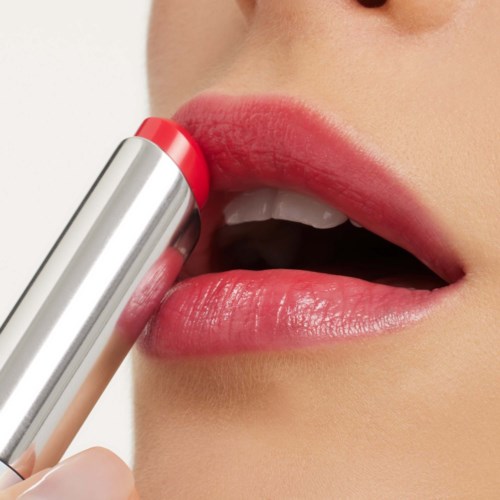 Close-up of a person applying pink lipstick to their lips.