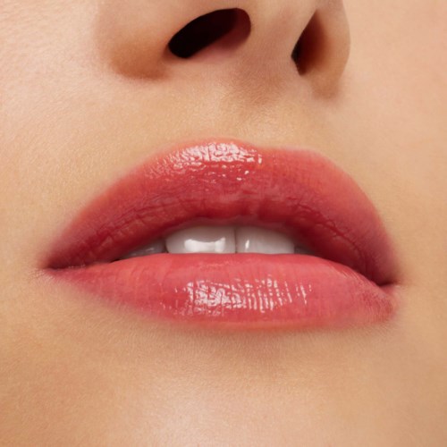 Close-up of lips showing glossy pink lipstick, slightly parted teeth, and clear skin.
