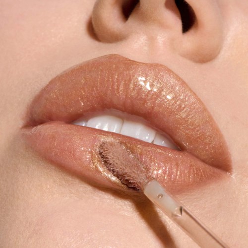 Close-up of lips with a lip gloss applicator applying lip gloss. The lips are slightly parted, showing teeth.