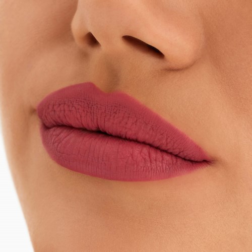 Nahaufnahme von Lippen mit mattem rosa Lippenstift und glatter Haut um den Mund.