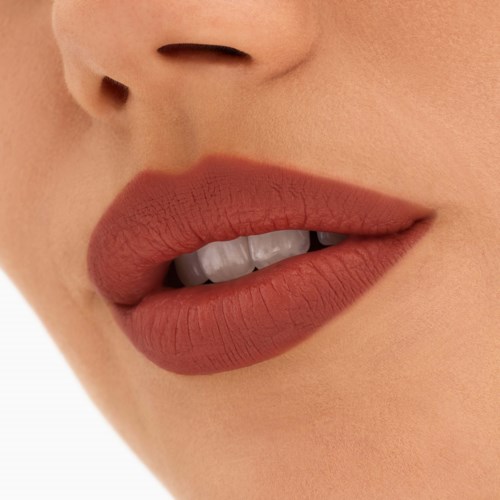 Nahaufnahme von Lippen mit mattem Lippenstift und kleinen Zähnen sichtbar, Teil eines Gesichts.