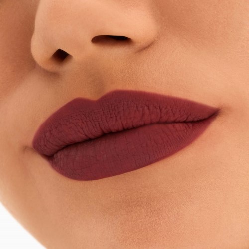 Nahaufnahme der Lippen mit mattem, dunklem Lippenstift und glatter Haut. Teil der Nase ist sichtbar.