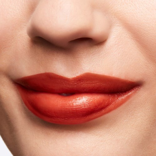 Close-up of a person’s lips with lipstick, part of a nose visible, smooth skin, gentle smile.