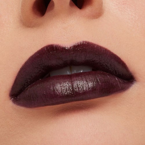 Close-up of lips with dark, shiny lipstick, showing slightly parted lips and smooth skin.