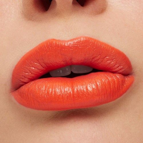 Close-up of lips in bright orange lipstick, with slightly parted lips revealing teeth.