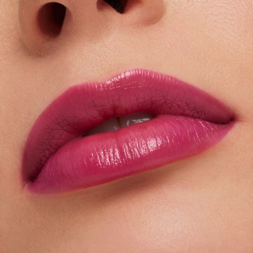 Close-up of lips with pink lipstick and visible skin pores near the nose.
