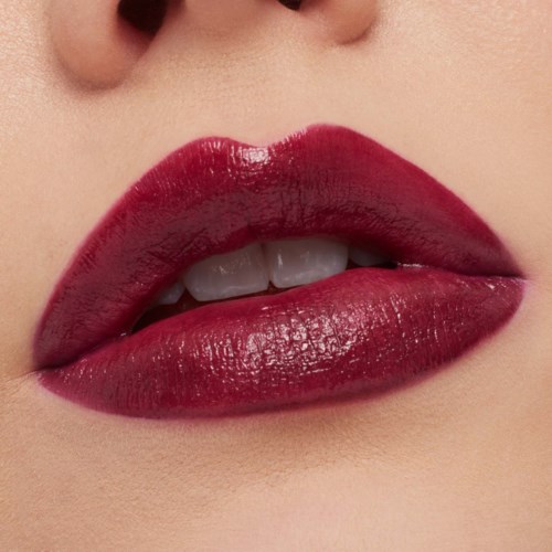 Close-up of lips with shiny dark red lipstick, slightly open showing part of teeth, smooth skin around.