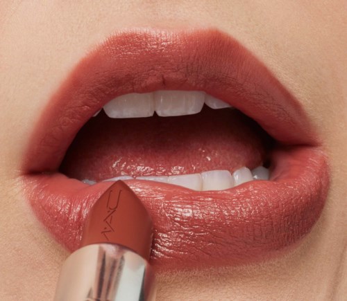 Close-up of lips with lipstick being applied, showing teeth and glossy skin.