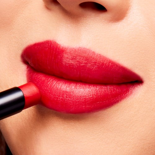 Close-up of lips applying red lipstick, with smooth skin and a small nose visible.