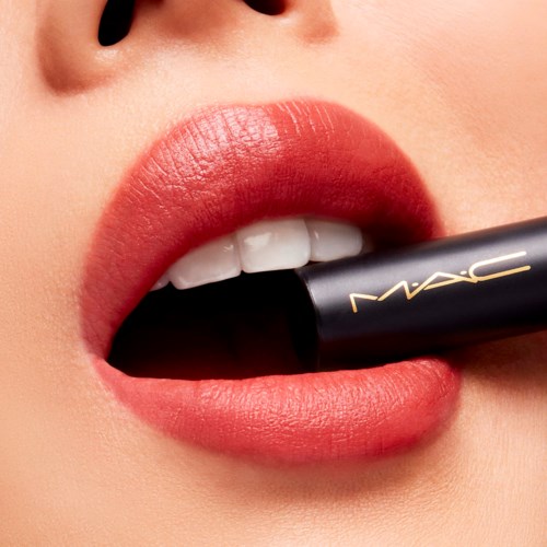 Close-up of lips with peach-colored lipstick and a MAC lipstick tube near the lips.