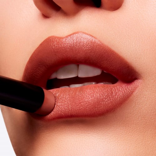 Close-up of lips, with lipstick being applied, showing part of the mouth and teeth.
