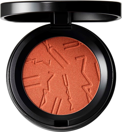 A round compact with coral-colored powder and textured, engraved pattern inside a black case.