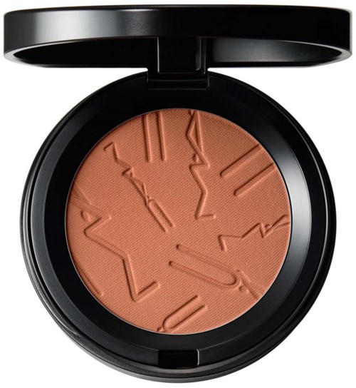 A makeup compact with embossed lines in a peach-colored powder. The compact has a black lid.