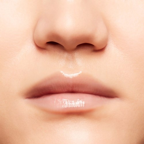 Close-up of a person's nose and lips with a small amount of white lip gloss.