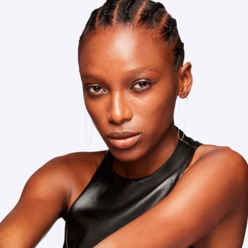 A woman with braided hair, wearing a black sleeveless top, looking directly at the camera.