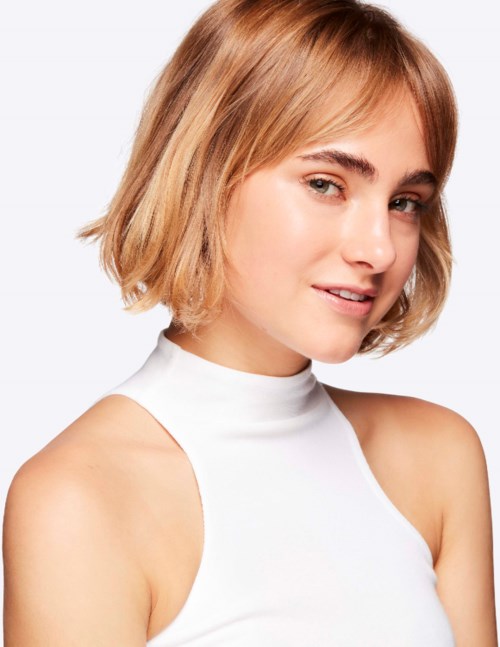A young woman with short blonde hair wearing a white sleeveless top, smiling slightly, facing slightly to the right.