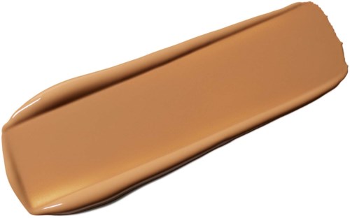 En beige flytende foundationprøve spredd på mørk bakgrunn.