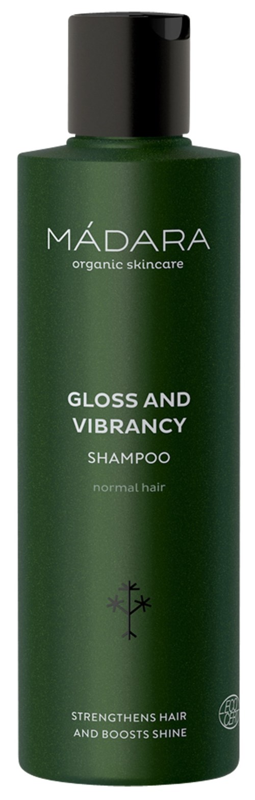 A green shampoo bottle with a black cap labeled 'MÁDARA' for normal hair, designed to make hair shiny and strong.