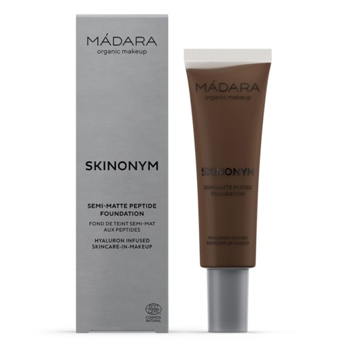 A brown foundation tube stands next to a silver box with black text, labeled as MADARA organic makeup Skinonym semi-matte foundation.