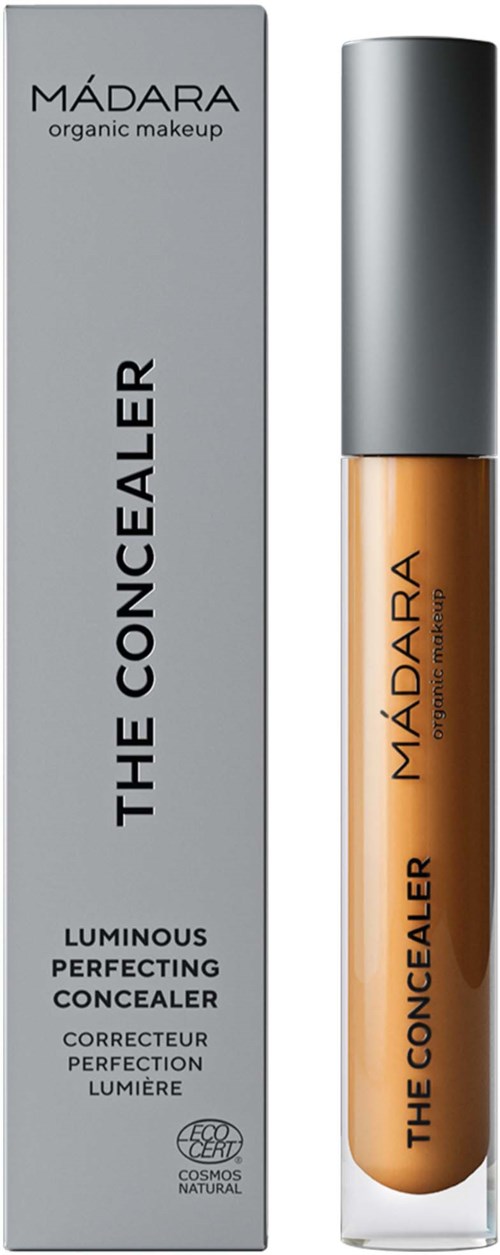 A beige concealer in a small glass bottle with a grey cap, next to a grey box labeled "MADARA" and "The Concealer."