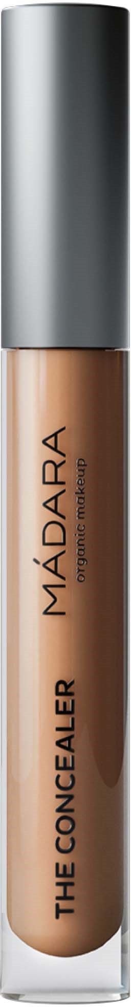 A concealer in a tube with a silver cap, labeled 'THE CONCEALER' by MADARA, on a black background.