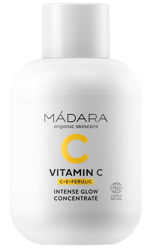 A white bottle of MÁDARA Vitamin C serum contains organic skincare, brightening concentrate, with C, E, and ferulic acid.