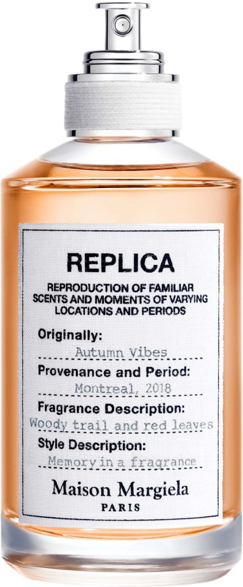 Een parfumfles met REPLICA-label, witte label, zilveren dop en roze vloeistof.