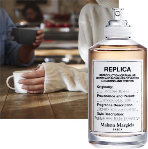 Een grote fles parfum met het label "REPLICA" op een houten tafel, mensen die bekers vasthouden op de achtergrond.