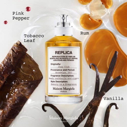 Ein Parfümflasche mit der Bezeichnung Replica, umgeben von Vanille, Tabakblatt, Rum, rosa Pfeffer und Karamellbonbons.