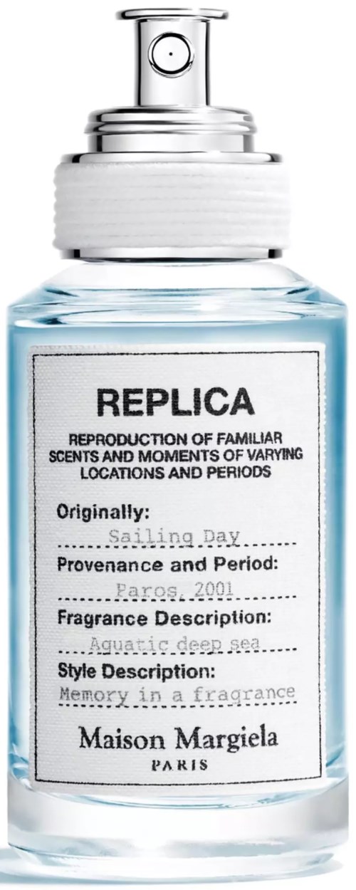 Eine klare Glasparfümflasche mit weißem Sprühkopf und einem Etikett mit dem Wort REPLICA von Maison Margiela.