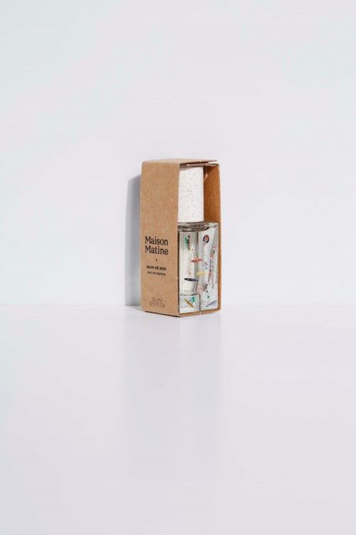A glass with a colorful design inside, next to a brown cardboard box. The box has text 'Maison Matine'.