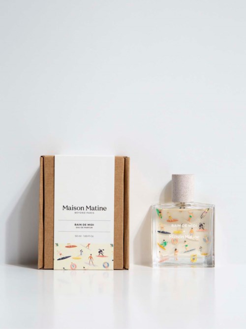 A perfume bottle and box with colorful, playful illustrations on a white surface and background.