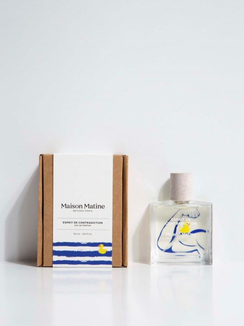 A perfume bottle with a light pink cap and a box labeled 'Maison Matine' with blue and yellow design.