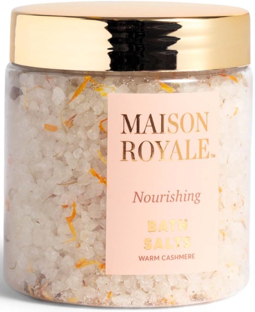 A jar of nourishing bath salts with warm cashmere scent, containing white and orange salt flakes.
