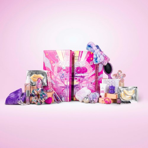 A pink surprise box with various colorful beauty and grooming products around it, including brushes, scrunchies, and accessories.