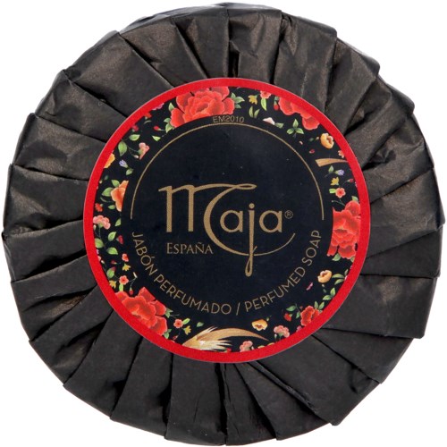 A round soap wrapped in black paper with a floral label showing red flowers and gold text.