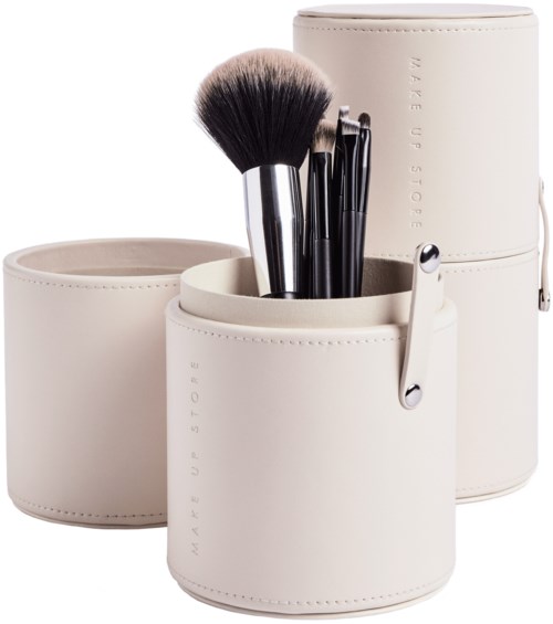 A white cylindrical makeup brush holder with brushes inside and a matching box.