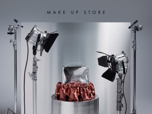 Hopea laukku pöydällä, jossa on pinkki röyhelöinen kangas, ja kolme studiovaloa ympärillä Make Up Store.