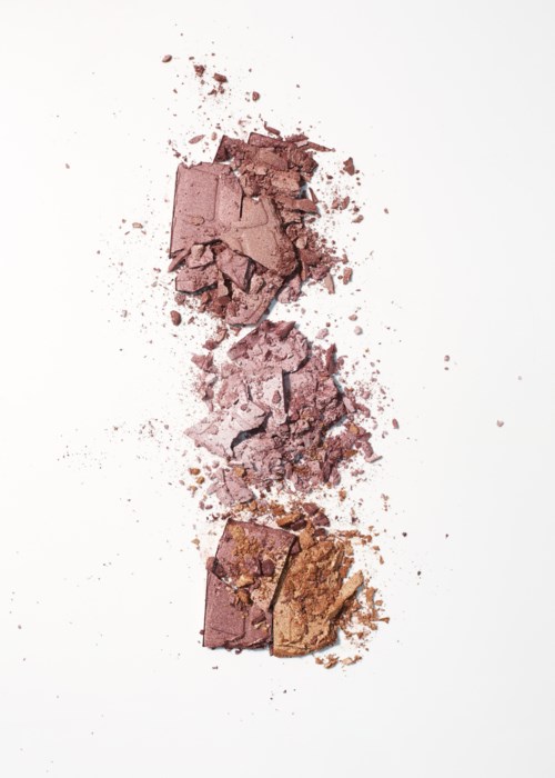 En vertikal linje av trasiga rosa och bruna makeuppuder på en vit bakgrund.