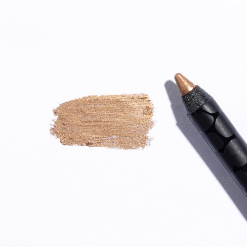Ett beige kritmärke ligger på vitt papper bredvid en svart och guldfärgad krita.