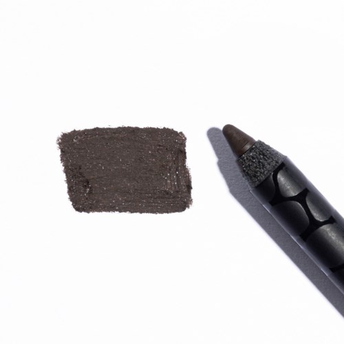 Een zwarte krijt met een bruinachtige punt, naast een zwarte vlek op wit papier.