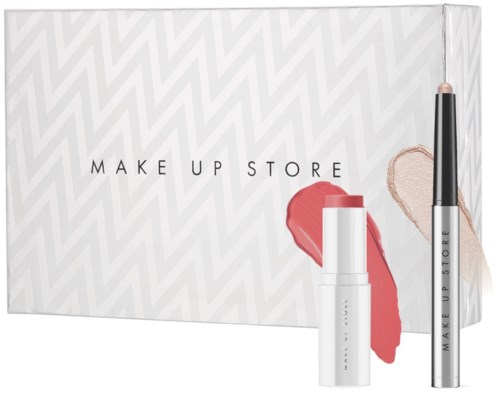 Een doos met make-up producten, inclusief lippenstift en concealer, op een patroonachtergrond. De doos heeft de tekst "MAKE UP STORE."